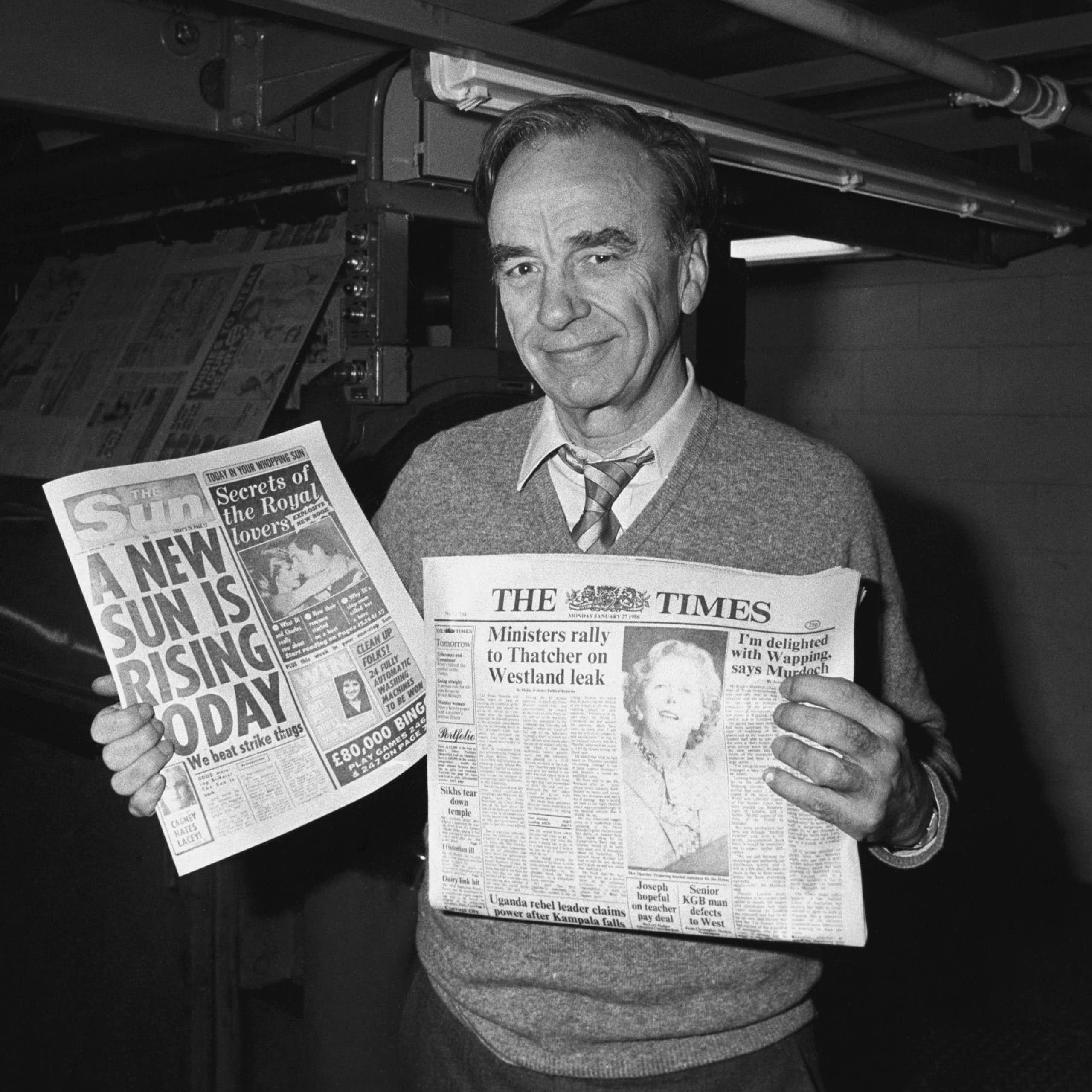 Rupert Murdoch holding newspapers at a print site in 1986.