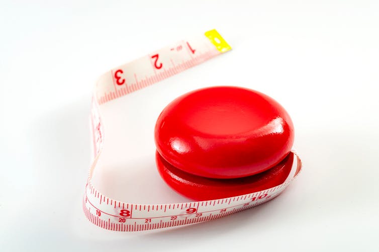 A red yo-yo with a measuring tape instead of a string