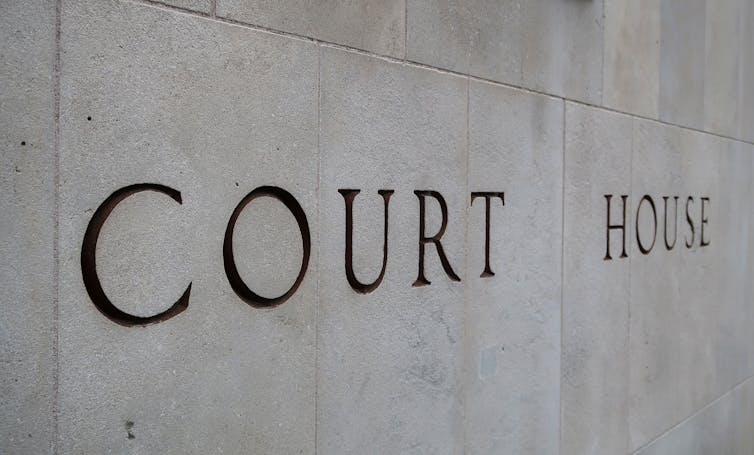 The words Court House are etched onto a concrete wall.