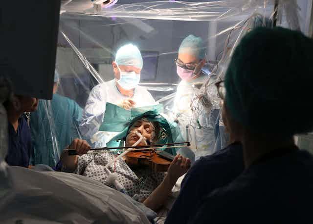 Mujer tocando el violín mientras se somete a una cirugía cerebral.