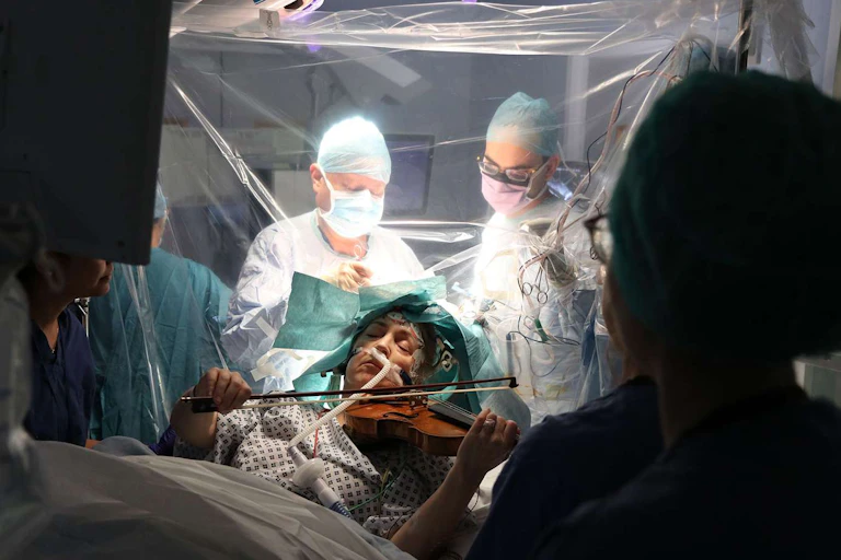 Mujer tocando el violín mientras se somete a una cirugía cerebral.