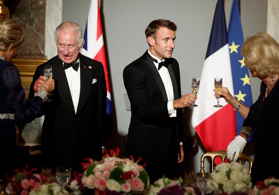 Le roi Charles et Emmanuel Macron trinquent avec leurs épouses respectives lors d'un banquet à la cravate noire. 