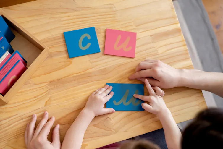 Una madre ayuda a su hija a descubrir las letras utilizando un alfabeto en bruto