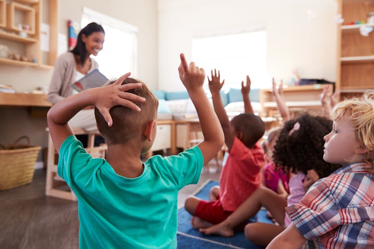 Pupils raise their hands to answer the teacher’s questions