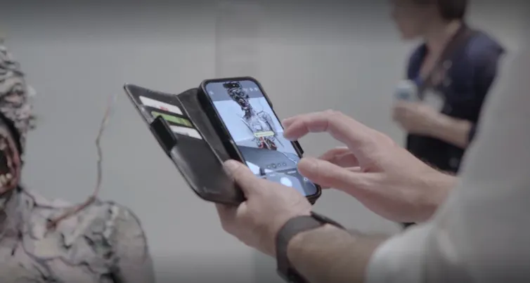 A hand holding cellphone seen photographing a troll.