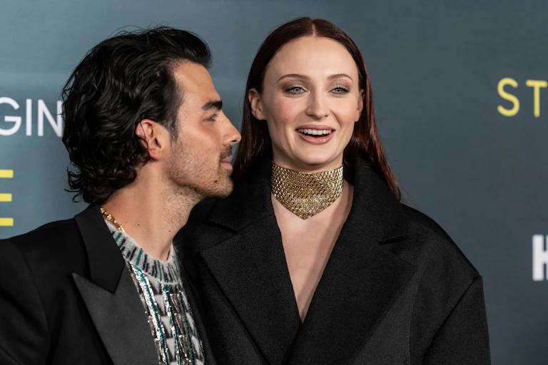 Sophie Turner and Joe Jonas at an industry event, Sophie is smiling and Joe is looking at her