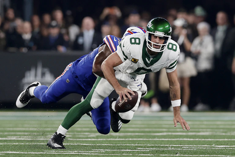 Football player holding ball in the process of being tackled.