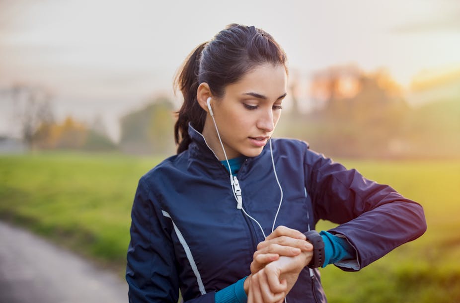 Une femme fait de la course à pied en écoutant de la musique et en portant une montre connectée