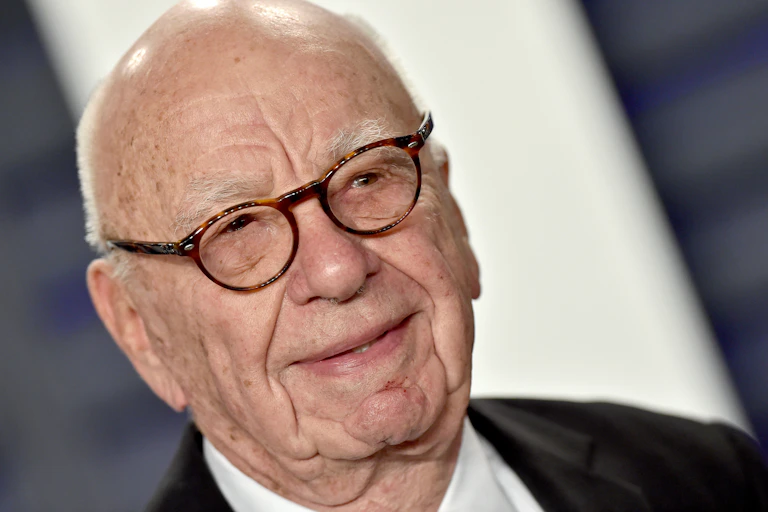 A balding man with glasses is photographed in closeup photo of his head and neck.
