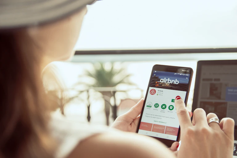 A woman searches through an Airbnb app on her mobile phone