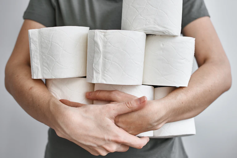 A man holds several rolls of loo paper.