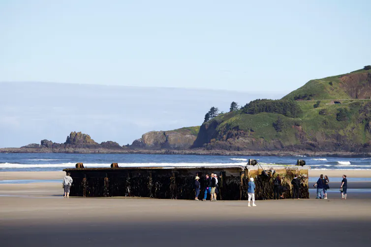 A large man-made structure washed onto a sandy beach.