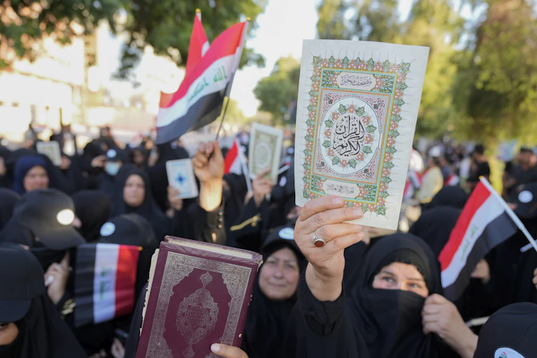 Women wearing the abaya hold up copies us the Quran during a protest.