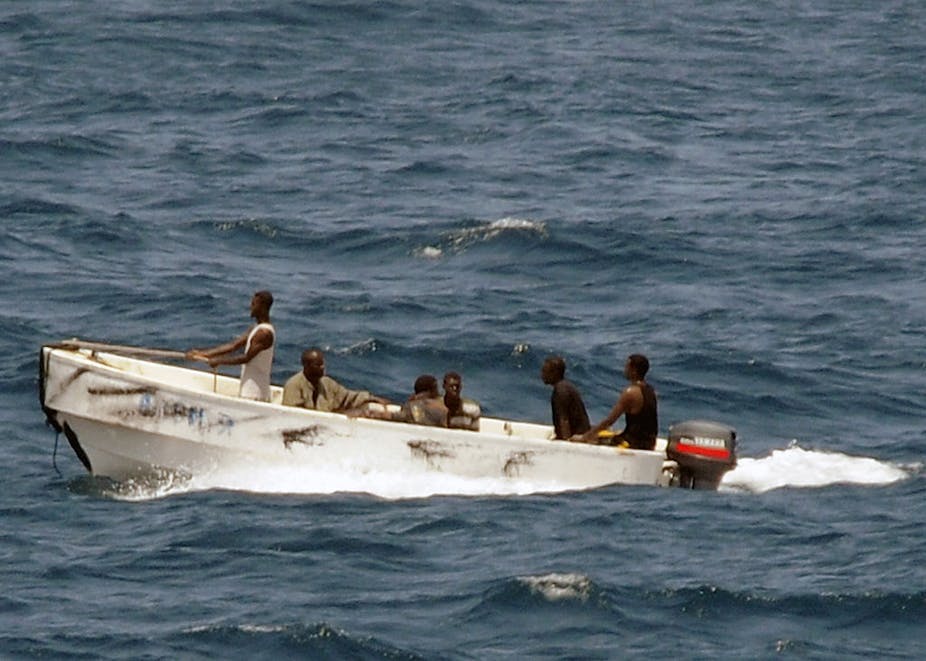 Six men sitting in a small speedboat in the middle of a large body of water