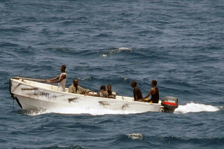 Six men sitting in a small speedboat in the middle of a large body of water
