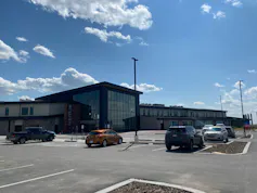 A building seen with cars in the front against a blue sky.