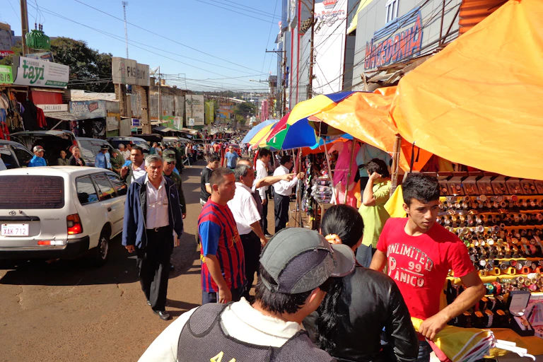People sell their wares on a crowded street full of shops and stalls.