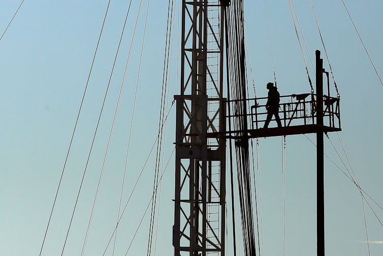 A worker walks across a platform high up on a oil rig.