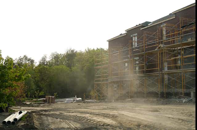 New houses under construction against a forest backdrop.
