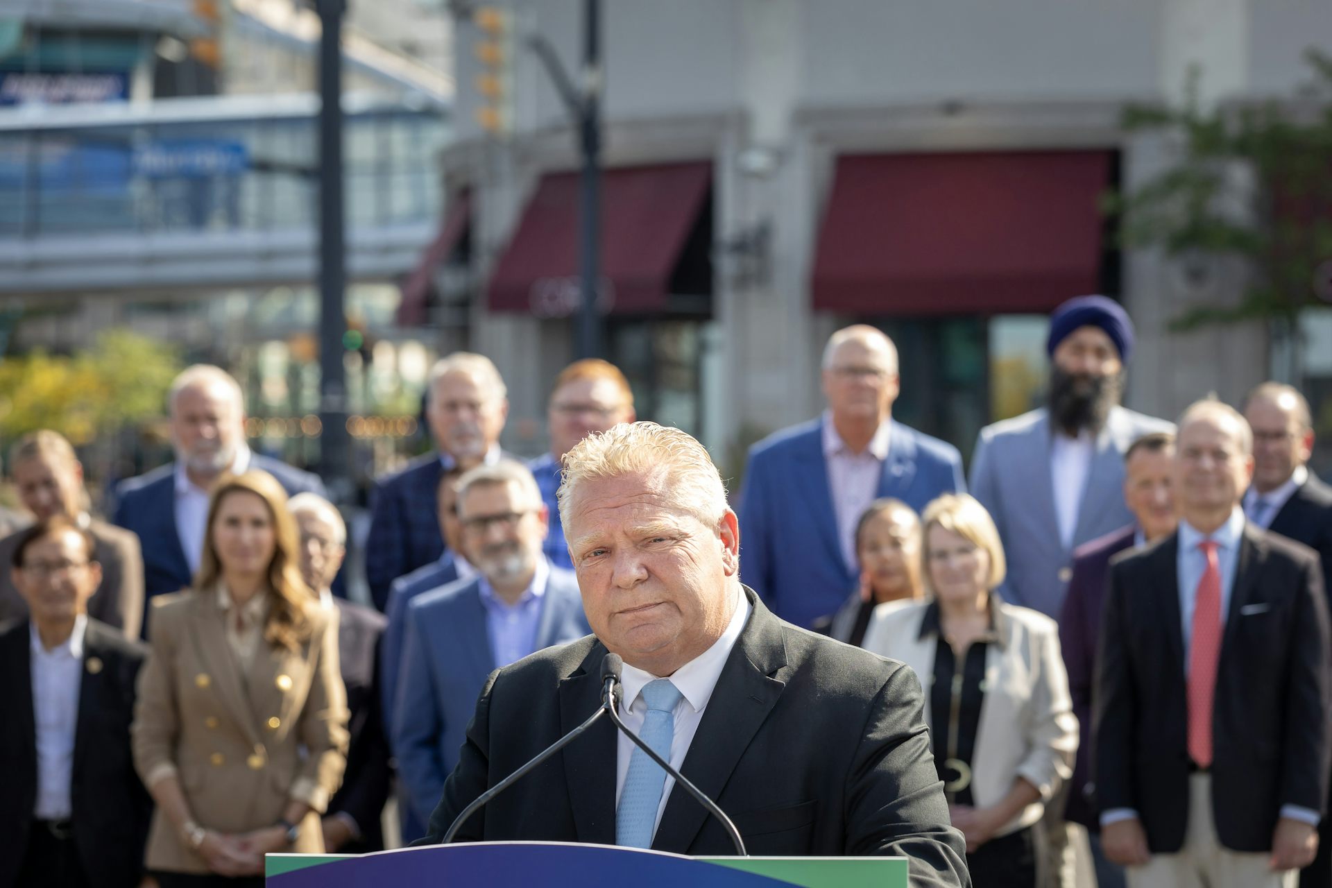 Doug Ford seen at a podium before two rows of people.