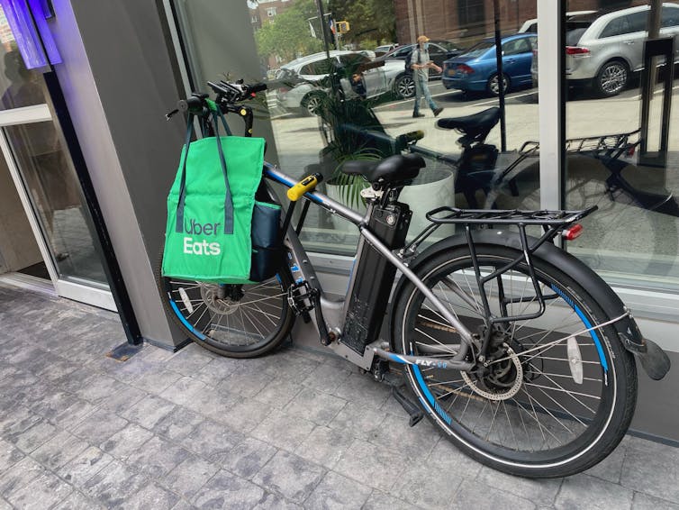 An e-bike with an Uber Eats bag hanging from the handlebars leans against a building.