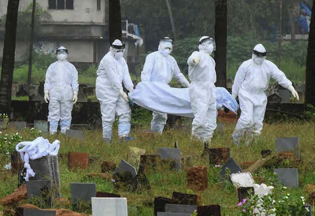 People in protective clothing carry the body of a person who died of Nipah virus