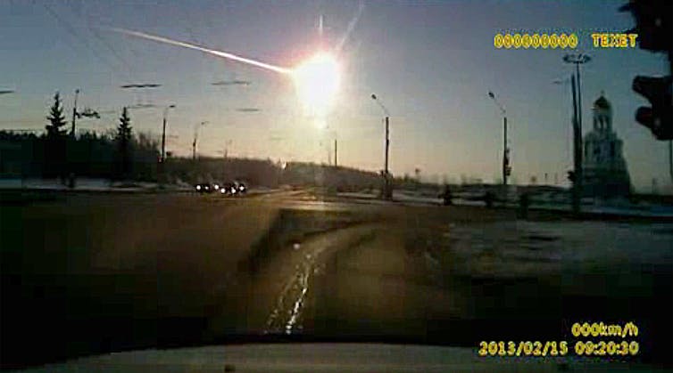 A screengrab from a dashboard camera video showing a bright fireball in the sky over a road.