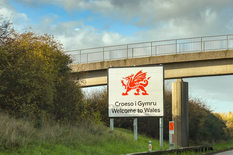 A bilingual sign with a large dragon saying 'Welcome to Wales'.