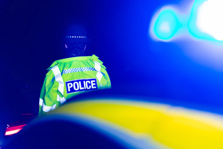 A police officer in a high-vis vest seen from behind, tightly cropped.