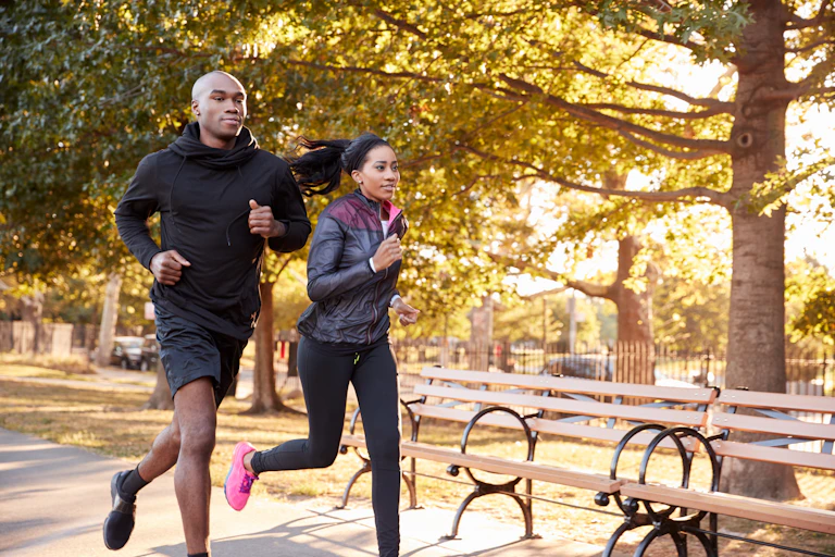 A young man and woman run beside each other.