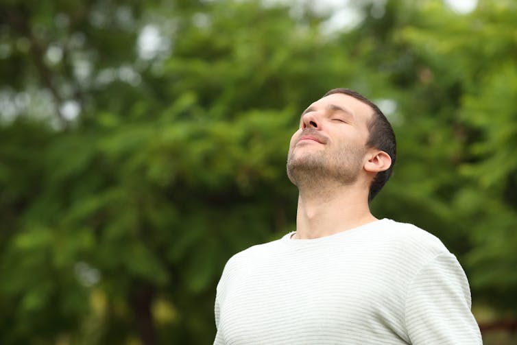 A man takes a deep breath of air through his nose.