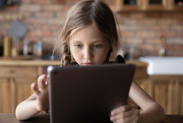 A young girl plays on an ipad