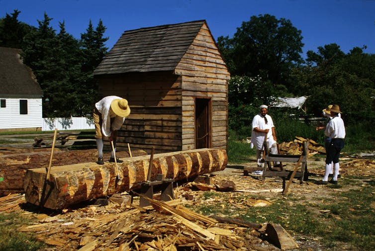 Three Black men holding axes are appearing to work as carpenters.