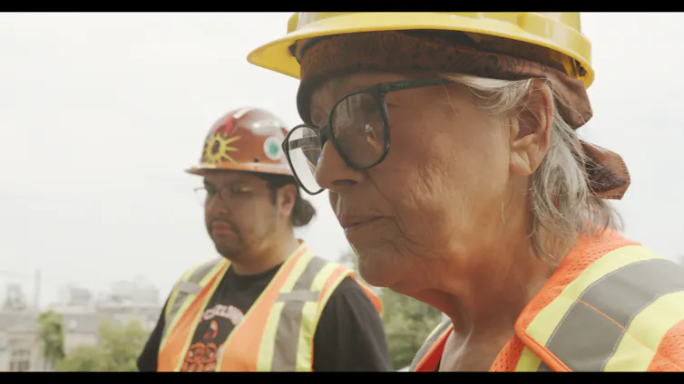 Close up photo of two people in hard hats and hi vis jackets.
