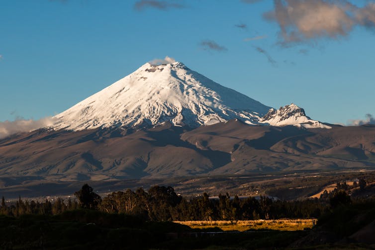 A volcano with an ice-covered summit seen from a distance.