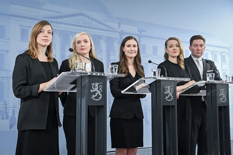 Ministers in Sanna Marin's government standing at podiums.