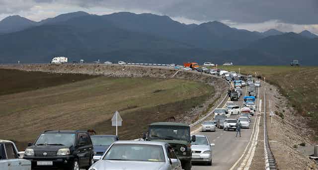 A queue of cars goes on for miles against a backdrop of mountians.