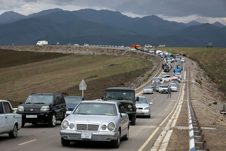A queue of cars goes on for miles against a backdrop of mountians.