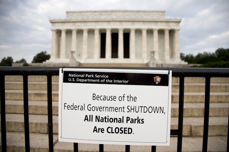 A sign reading 'Because of the Federal Government SHUTDOWN All National Parks are Closed' is posted on a barricade in front of the Lincoln Memorial.