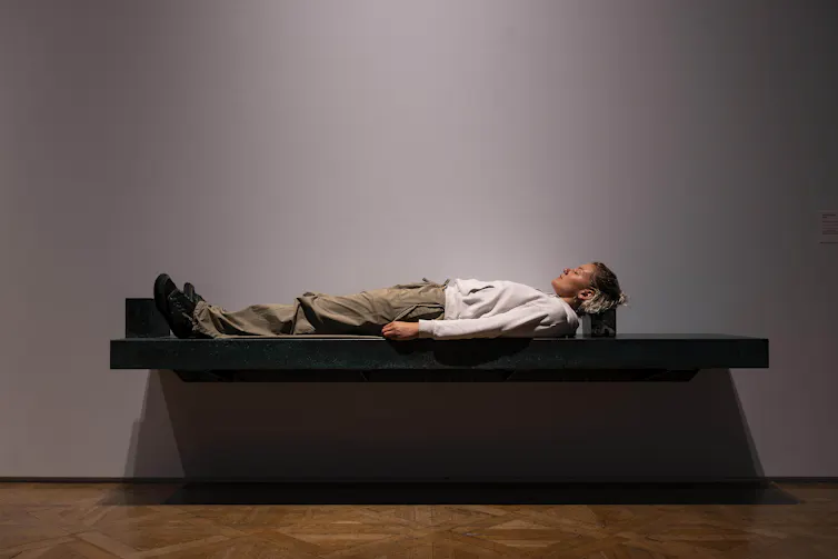 A man lying on a green bench