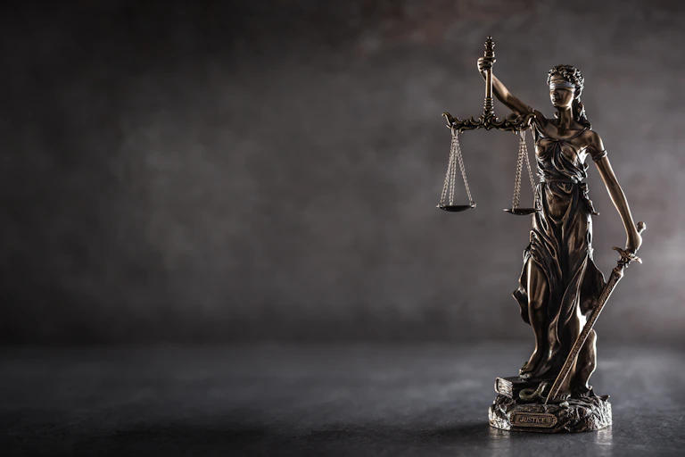 A statue of the figure of Justice, blindfolded and holding a scale in one hand and a sword in the other.