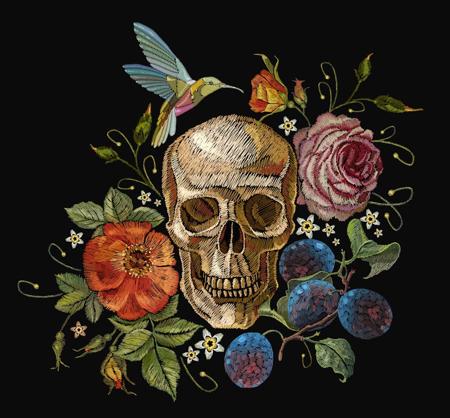Embroidered skull nestled among flowers and a hummingbird
