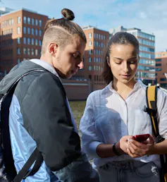 Two youth seen looking at a smartphone.