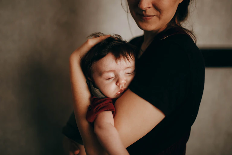 A mother holds a sleeping baby.