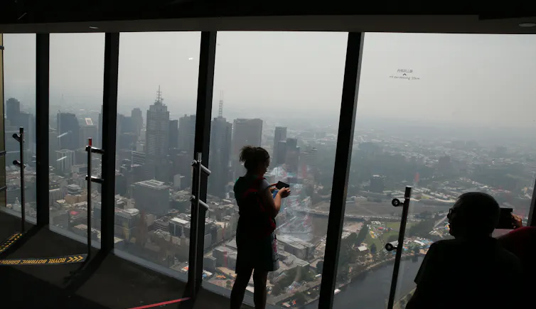 woman behind glass looking at smoky melbourne