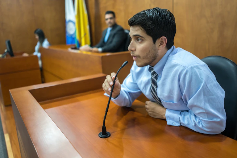 man leans into microphone in courtroom