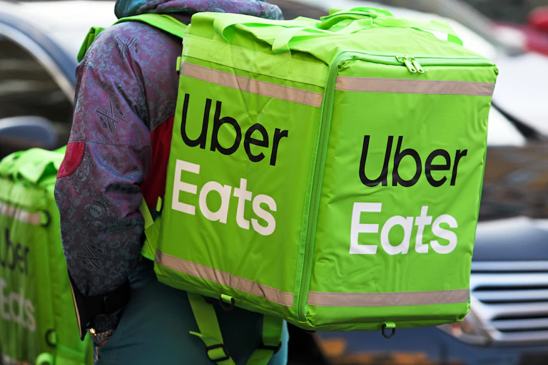 A person carries an Uber Eats bag on their back.