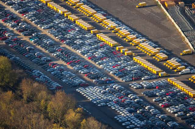 An aerial view of rows of parked cars and vans.