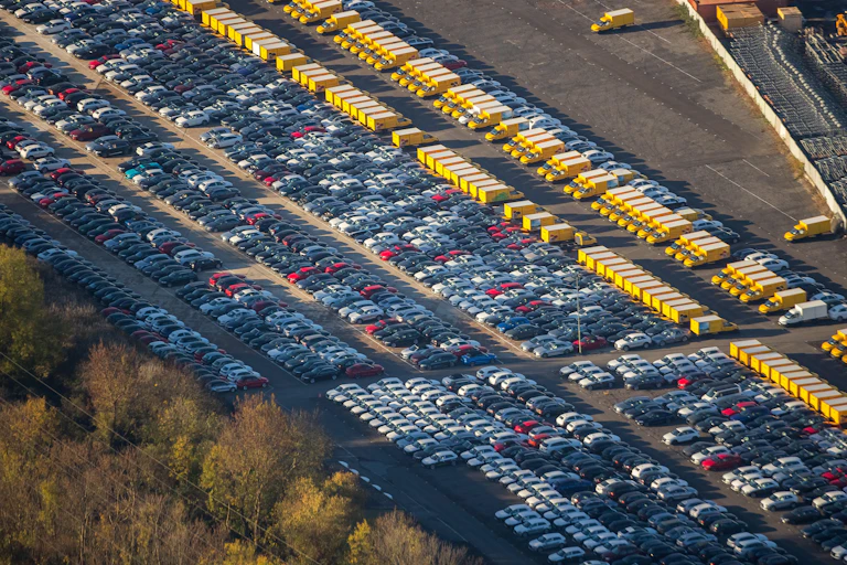 An aerial view of rows of parked cars and vans.