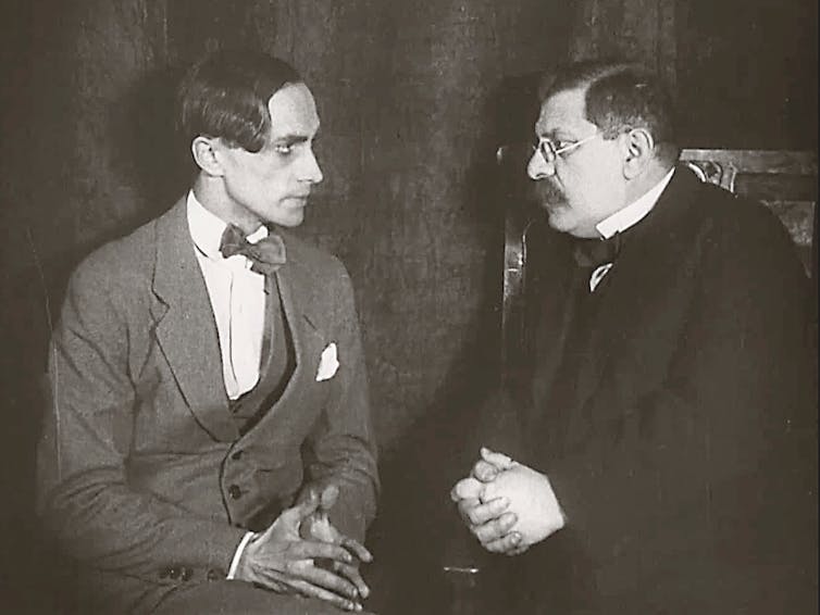 a black and white film still of two men in suits